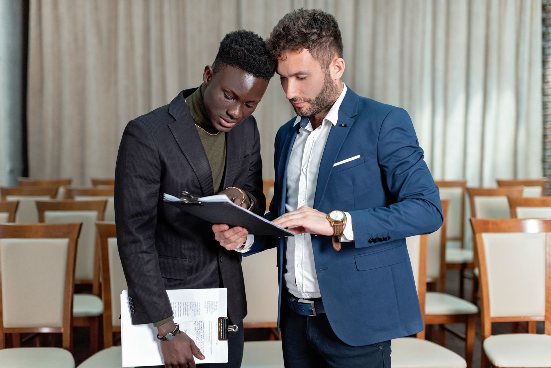 Two business professionals engaged in a detailed document review in a conference room